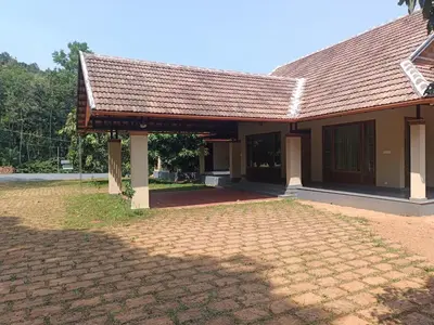 a house with a tile roof and a brick driveway at Silvertrails in Kalpetta