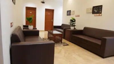 a living room with two couches and a table at Neom's Golden Gate in Alwaye