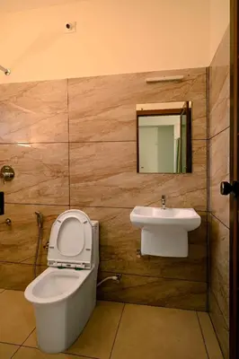 a bathroom with a toilet and a sink at Spectrum stays in Ambalavayal