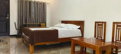 a bedroom with a bed and a desk and a table at Dream Nest Resort in Mettuppālaiyam