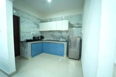 a kitchen with blue cabinets and a stainless steel refrigerator at Nandan Enclave in Mysore