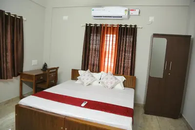 a bedroom with a bed and a dresser and a mirror at NR HEAVENZ Near Rajagiri Hospital in Alwaye