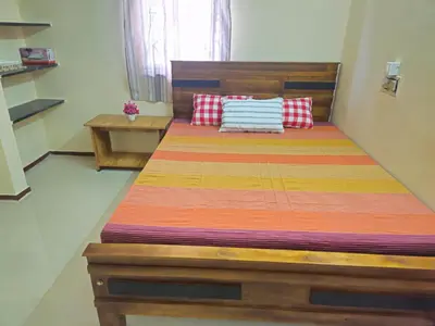a bedroom with a wooden bed with pillows on it at SHI's Ganga 2BHK in GN Mills, Ganga Hospital, Women's Care Coimbatore in Coimbatore