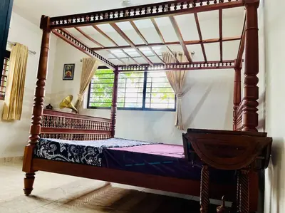 a wooden canopy bed in a room with a window at Haven Stay Manor in Kotamangalam