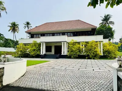 a large white house with palm trees in front of it at Haven Stay Manor in Kotamangalam