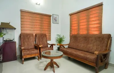 a living room with two chairs and a couch and a table at Swapna Home Suites in Nedumbassery
