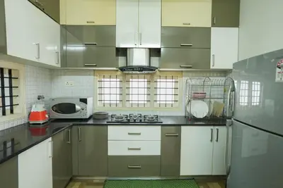 a kitchen with white cabinets and a microwave at Swapna Home Suites in Nedumbassery