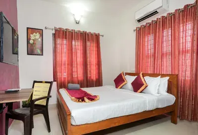 a bedroom with a bed and a table and a desk at Swapna Home Suites in Nedumbassery