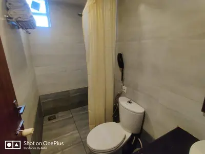 a bathroom with a toilet and a phone on the wall at Sreepathi Indraprastha in Guruvāyūr