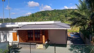 a small building with a fence in front of a mountain at Dream Nest Villa Wayanad in Kalpetta
