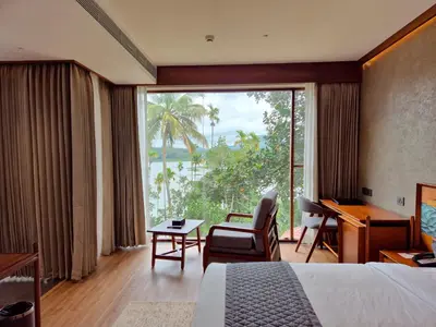 a hotel room with a bed and a large window at Sterling Lontano Waterfront Wayanad in Meppādi