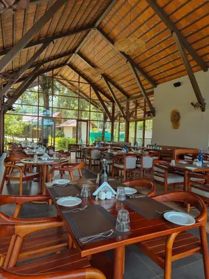 a dining room with wooden tables and wooden chairs at Sterling Lontano Waterfront Wayanad in Meppādi
