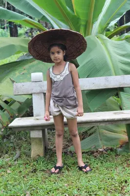 a little girl wearing a hat standing on a bench at Great Hornbill Serviced Villa , Nilambur in Kālikāvu
