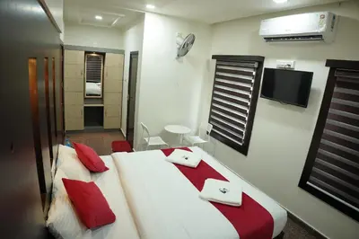a bedroom with a bed with red pillows and a tv at Hill Club Square in Malappuram