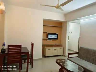 a living room with a couch and a table and a tv at VVP Service Apartments & Airport Suits in Cochin
