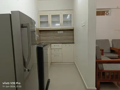 a small kitchen with a refrigerator and some chairs at VVP Service Apartments & Airport Suits in Cochin