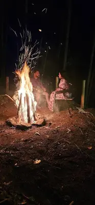 two people sitting around a fire in the dirt at The Soul Of Vattavada in Vattavada