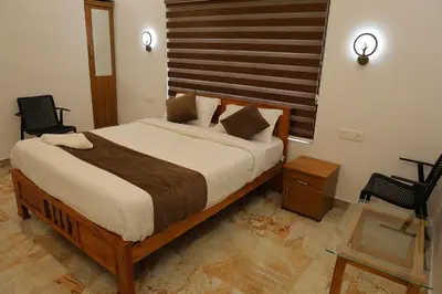 a bedroom with a large bed and two chairs at Josebaa Inn in Vythiri