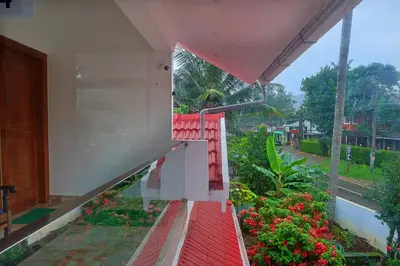 a balcony with a red bench and some flowers at Josebaa Inn in Vythiri