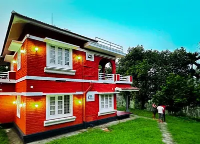 a red house with two people standing in front of it at Churuli Bungalow in Ambalavayal