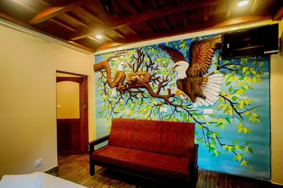 a room with a wall with a painting of birds at Falcon Riverview Resorts in Kuttampuzha