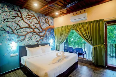 a bedroom with a tree mural on the wall at Falcon Riverview Resorts in Kuttampuzha