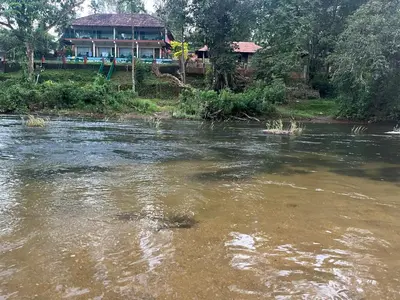 a view of a river with a house in the background at Falcon Riverview Resorts in Kuttampuzha