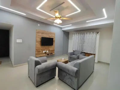 a living room with two chairs and a flat screen tv at Nandan Elite in Mysore