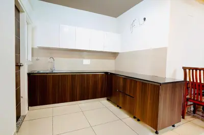 a kitchen with wooden cabinets and a sink at Elite Enclave - Mysore - 2BHK Luxury Serviced Apartments in Mysore