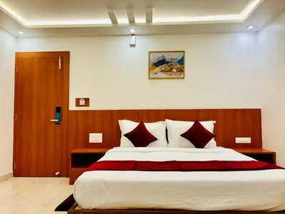 a bedroom with a large bed with red and white pillows at Hotel Starfinch Inn in Kushālnagar