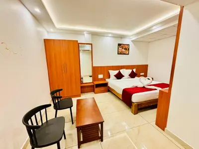 a bedroom with a bed and a table and a chair at Hotel Starfinch Inn in Kushālnagar