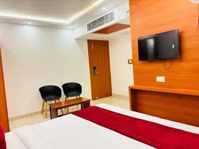 a bedroom with a bed and a tv on the wall at Hotel Starfinch Inn in Kushālnagar