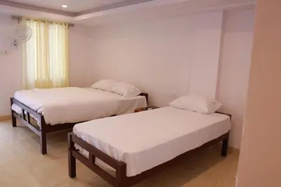 two beds in a room with white walls at Palatty Residency in Angamali