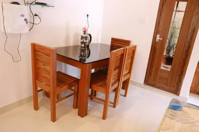 a dining room table with two chairs and a vase at Palatty Residency in Angamali