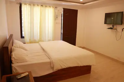 a bedroom with a white bed and a television at Palatty Residency in Angamali