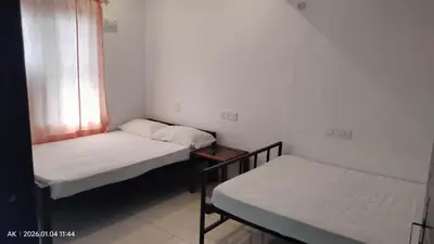 two beds in a small room with a window at Palatty Residency in Angamali