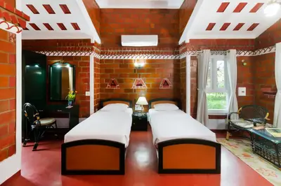 a room with four beds in a brick wall at Kairali - The Ayurvedic Healing Village in Palakkad