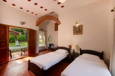 a bedroom with two beds and a window at Kairali - The Ayurvedic Healing Village in Palakkad