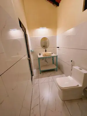a bathroom with a toilet and a sink and a mirror at The Road's End in Gonikoppal