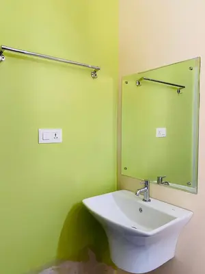 a green bathroom with a sink and a mirror at O'live Inn Wayanad Apart-Hotels in Vaduvanchal