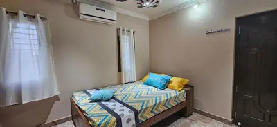 a bedroom with a bed with blue and yellow pillows at SHI's Thulasi 2BHK in Coimbatore Near to Karpagam College, Palakkad Highway, Rathinam College and More in Coimbatore