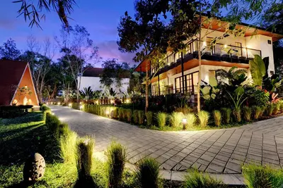 a building with lights on the side of a street at Sandesh Water Edge Kabini in Begūr