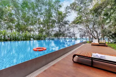a pool with a bench and a red raft in the water at Sandesh Water Edge Kabini in Begūr