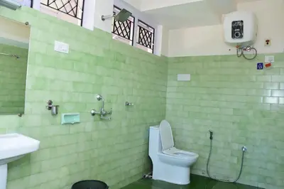 a green bathroom with a toilet and a sink at Rosewood 1 in Ooty