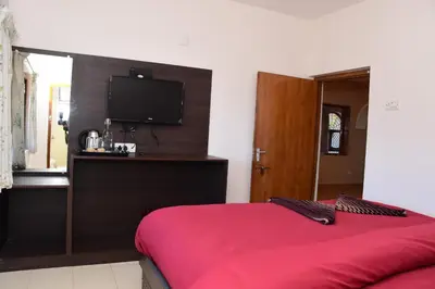 a bedroom with a red bed and a flat screen tv at Rosewood 1 in Ooty