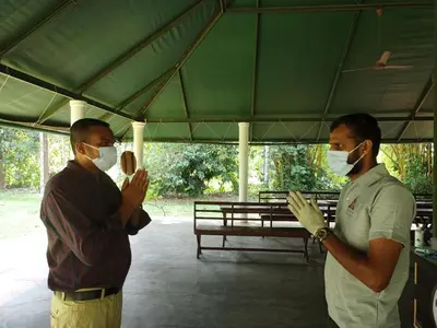 two men wearing face masks standing under a tent at Amritara Riverside Camp in Thattakād