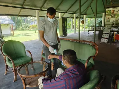 a man with a mask on his face and a man standing at Amritara Riverside Camp in Thattakād