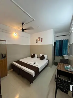 a bedroom with a bed and a desk in it at Priya lodge in Kozhikode