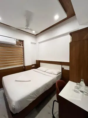 a small room with a bed and a table at Welcome Hotels in Trichūr
