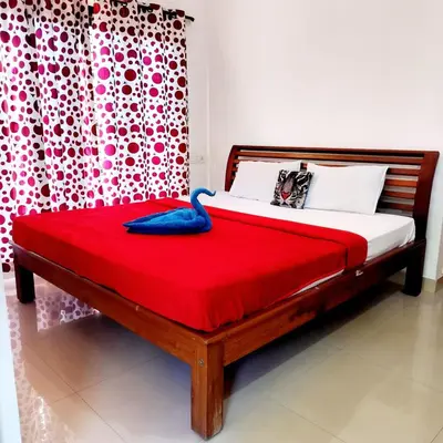 a bedroom with a bed with a red blanket and a curtain at Coorg Sunway home stay in Madikeri